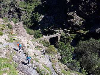 Photo of scenery in Alpujarras with an old bridge and some people hiking on old paths